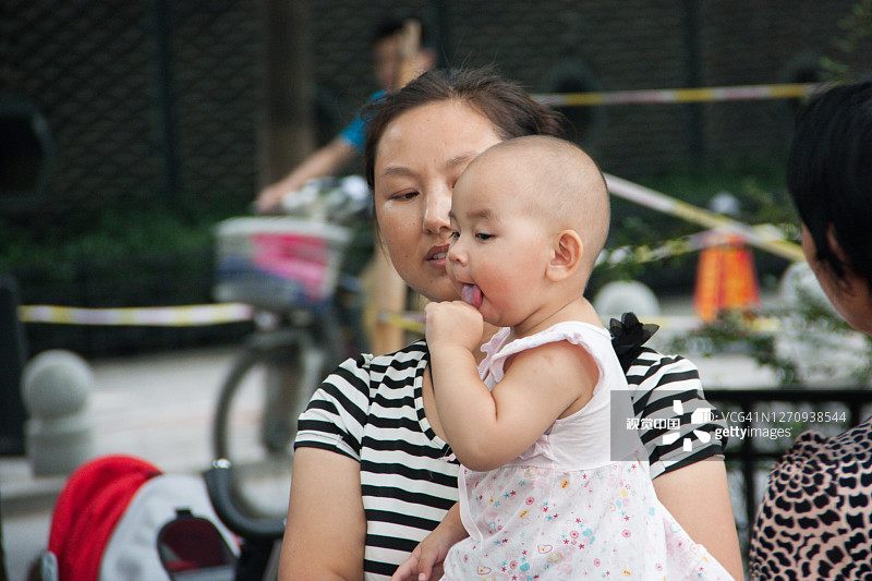 北京胡同里，母亲抱着一个孩子。图片素材