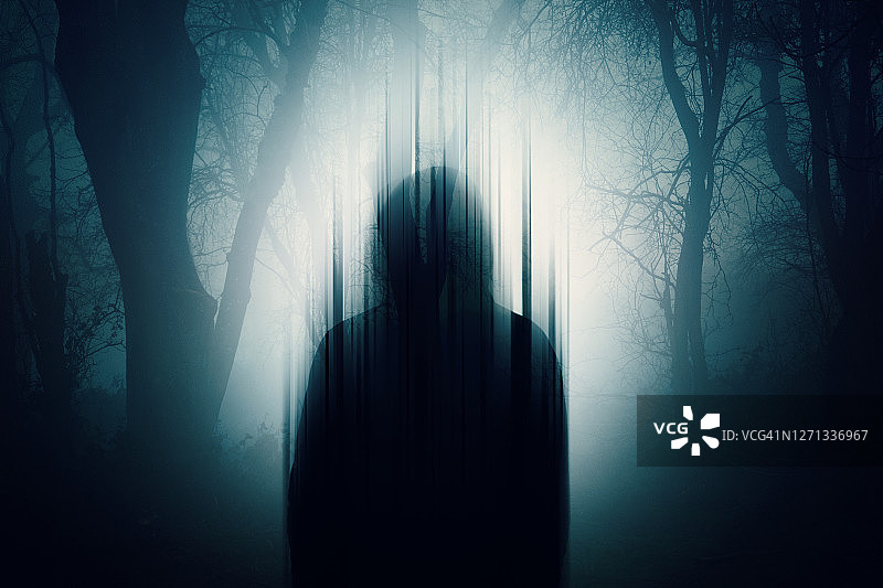 一张双重曝光的剪影一个神秘的人戴着头巾没有脸。夜晚站在森林里。用一个小故障编辑图片素材