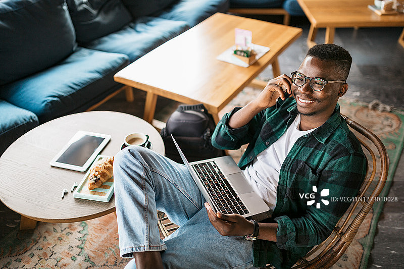 一个快乐的年轻非洲裔美国人在网上工作的高角度的咖啡馆图片素材