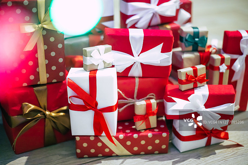用彩灯装饰的圣诞树和许多彩色的礼盒在家庭的房间里图片素材