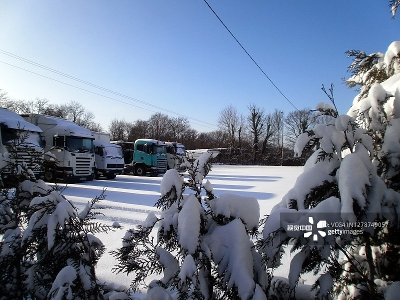 满是雪的冷杉。天气很好，蓝天和阳光。你可以看到一辆卡车停在那里。图片素材