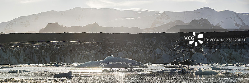由于气候变化和全球变暖，冰川和冰盖正在融化，日落时分的Jokulsarlon泻湖上的冰山，后面是Breidamerkurjokull冰川，冰岛东南部，欧洲图片素材