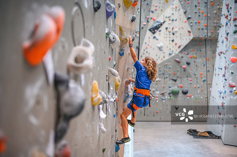 强壮的7岁男孩伸手抓住攀岩墙图片素材