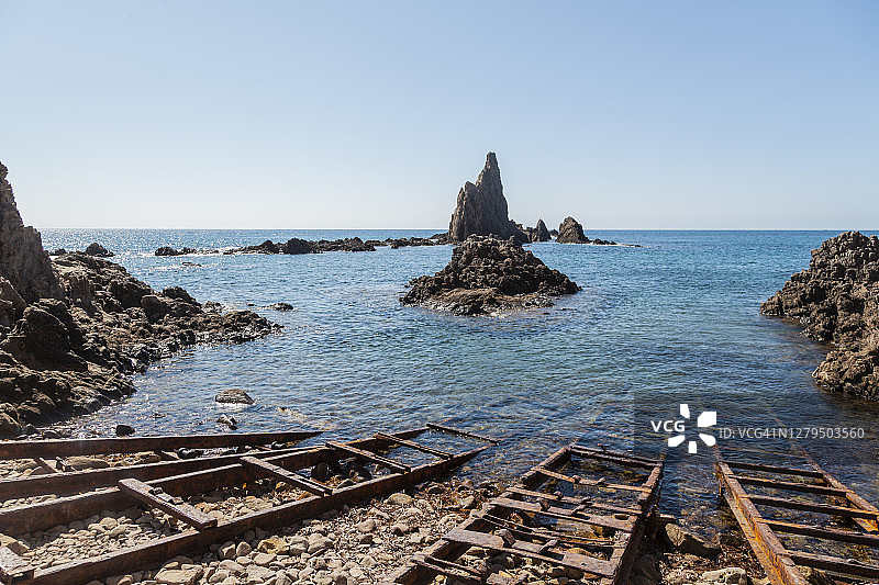 在卡波德加塔的海滩和多岩石的海岸，有火山岩和旧金属栏杆，捕鱼船。Cabo de Gata - Nijar自然公园，Arrecife de las Sirenas，生物圈保护区，Almería，安达卢西亚，西班牙图片素材