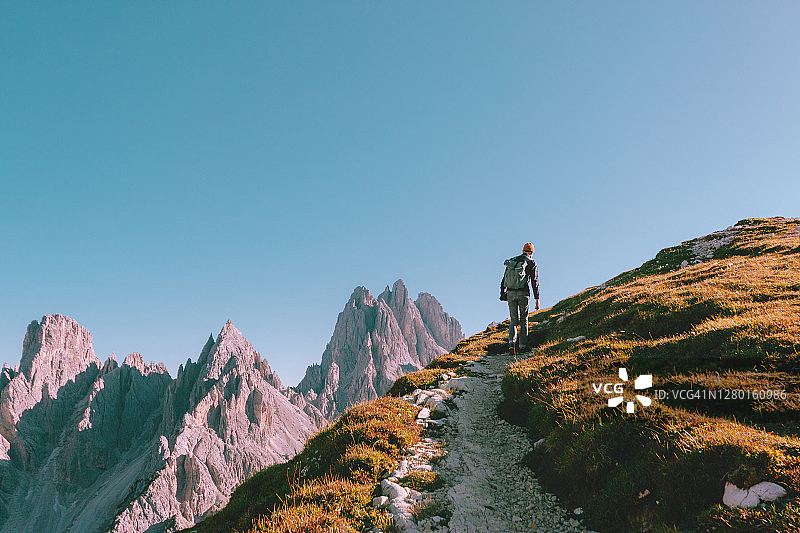 一个人在岩石的边缘徒步行走，望向地平线。意大利的阿尔卑斯山脉靠近拉瓦雷多山。图片素材