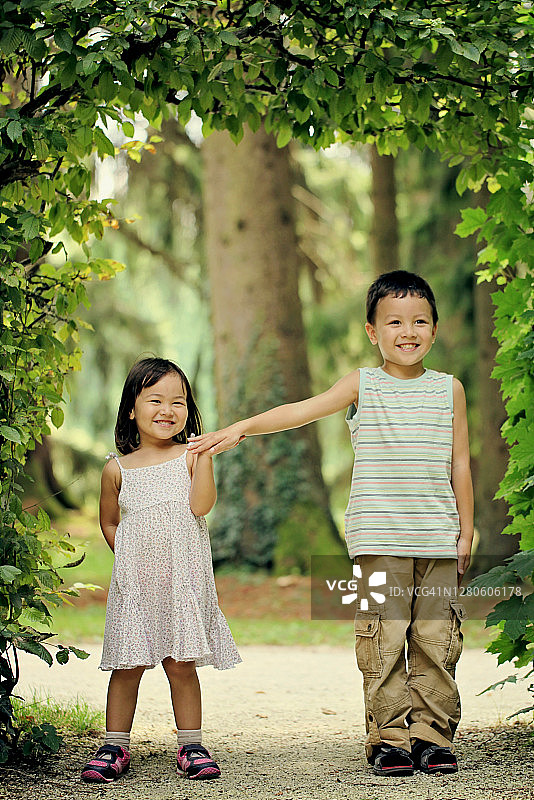 兄弟姐妹的肖像与牙齿微笑举手击掌在公园。图片素材