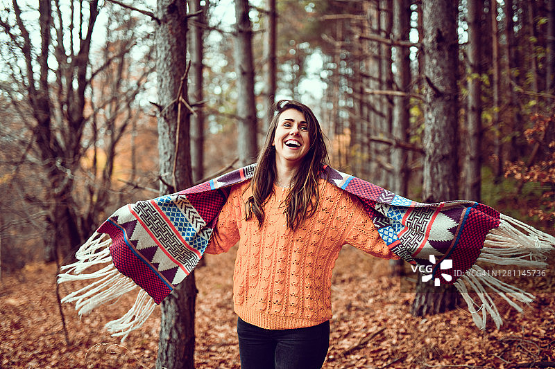 穿着羊毛衫和披肩的快乐女性在森林里享受秋天图片素材