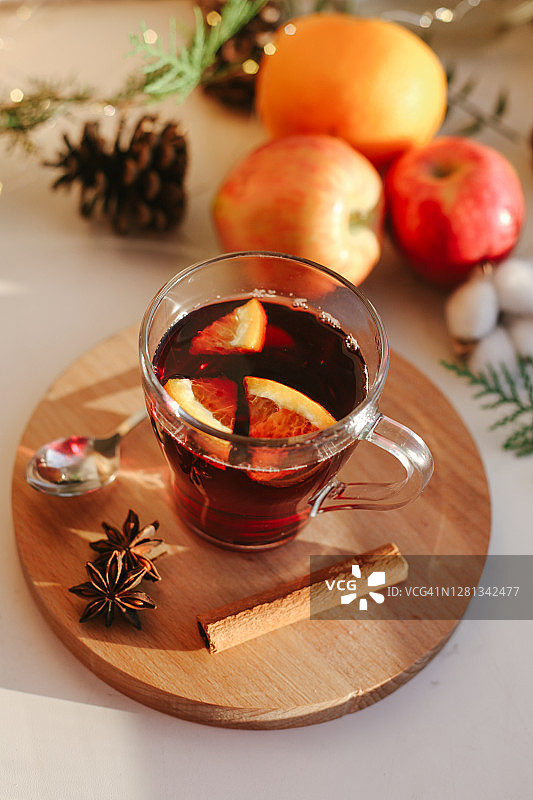 热红酒，用玻璃杯盛在窗台上的冬季热饮，家里的室内细节，还有橙子、苹果、香料和天然的圣诞装饰品图片素材