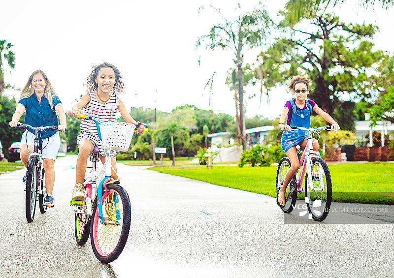 一家人骑自行车，母亲和女儿骑在郊区的社区图片素材