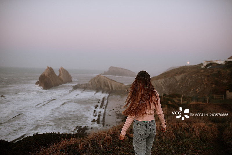 一个年轻女人在海边的后视图图片素材