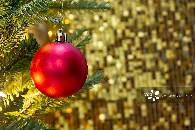 红色的小装饰品挂在圣诞树上，金色的背景图片素材