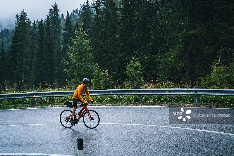 在雨中骑公路自行车的人在潮湿的路上骑行图片素材