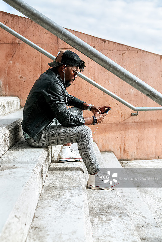 中年男子坐在城市的台阶上玩手机图片素材