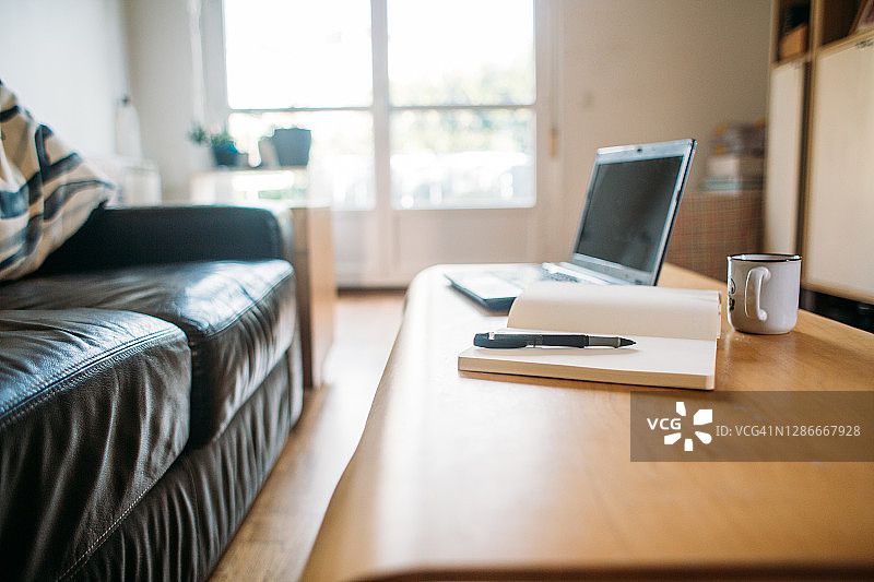 咖啡，笔记本电脑和一个带笔的白色笔记本可以在家里工作图片素材