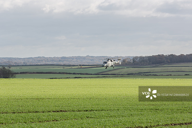 一架军用直升机低空飞过农田图片素材