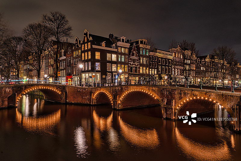 阿姆斯特丹城市拥有美丽的运河、桥梁和房屋。更美丽的是在一个黑暗的夜晚在仲冬图片素材
