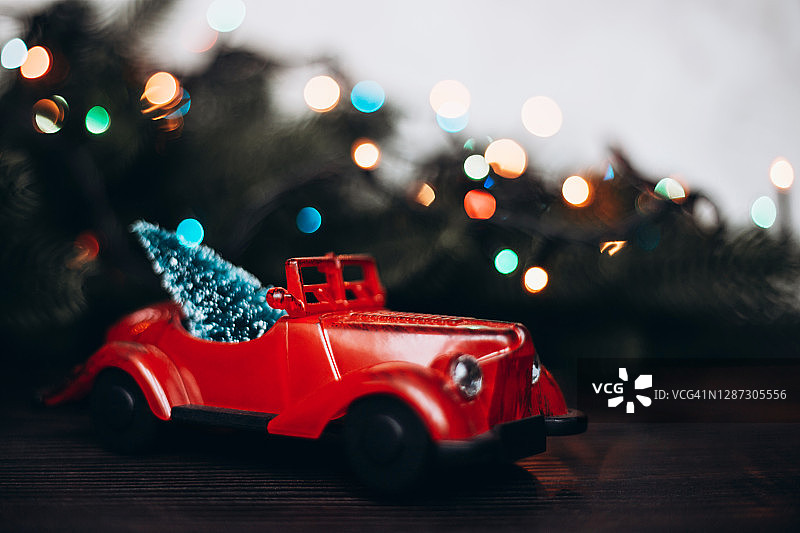 红色玩具车与圣诞树在黑暗的背景和花环图片素材