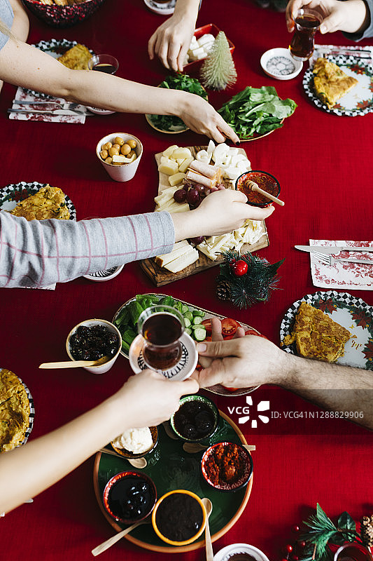 传统的土耳其早餐，土耳其茶，煎蛋卷和奶酪盘，红色背景的桌子。新年早晨，一位妇女正端着茶图片素材