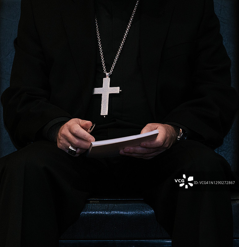 牧师胸前挂着十字架，手里拿着一本书图片素材