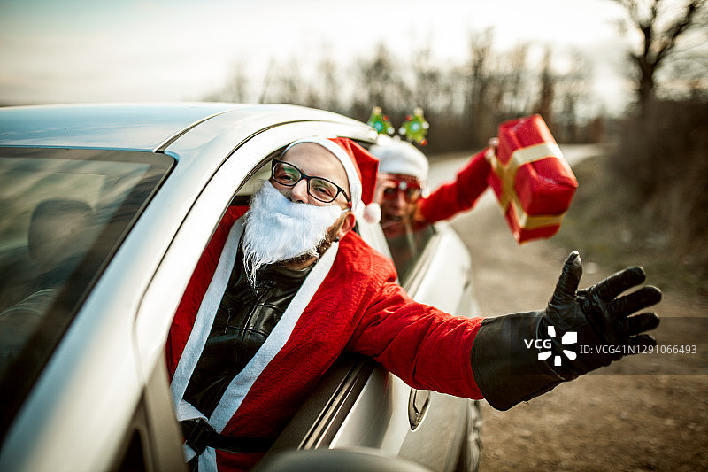 年轻的圣诞老人开车和他的女性朋友玩得开心图片素材