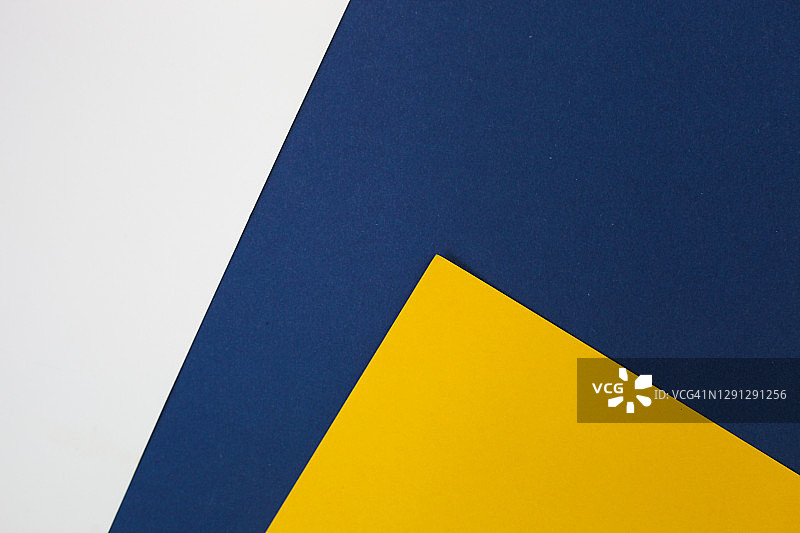 几何抽象纸背景的蓝色，黄色和白色的颜色。时髦的现代平板lay。图片素材