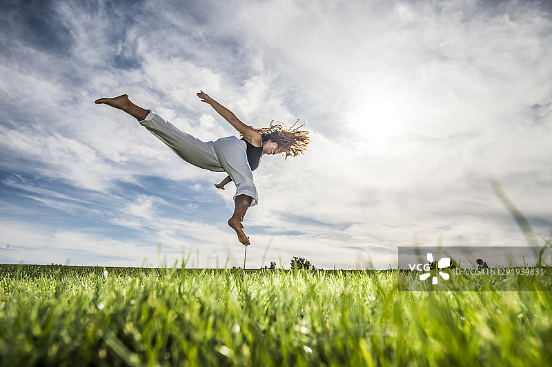 女运动员在云雾缭绕的公园草地上的半空中跳跃图片素材