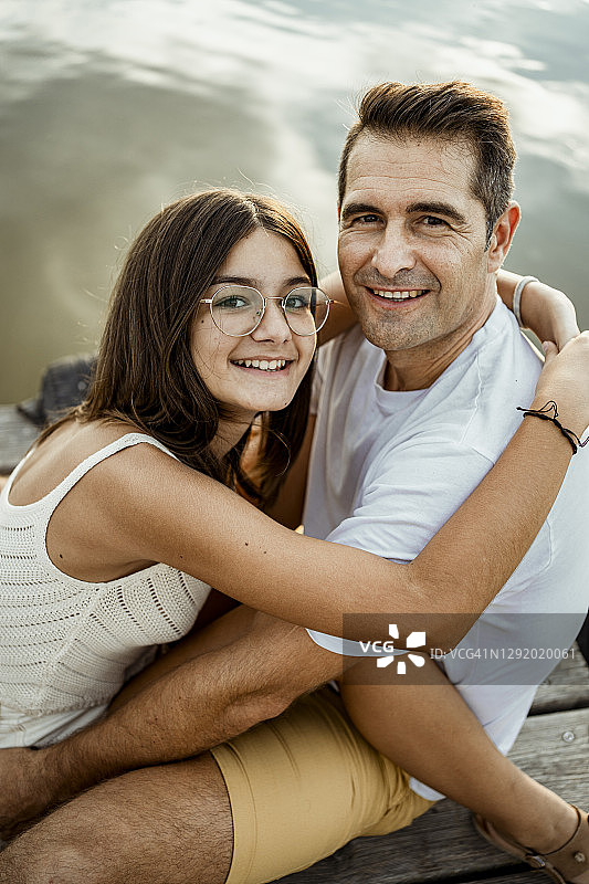 微笑的女儿拥抱父亲坐在码头图片素材