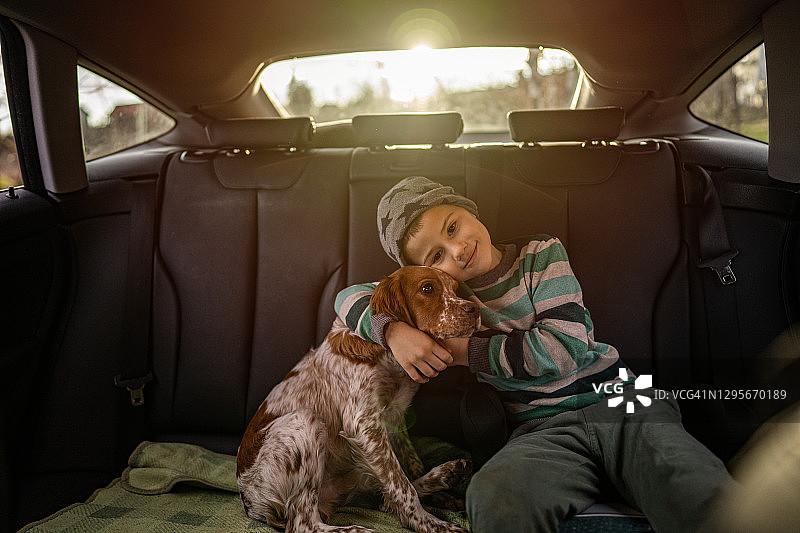 一个小男孩和他的狗坐在汽车后座上图片素材