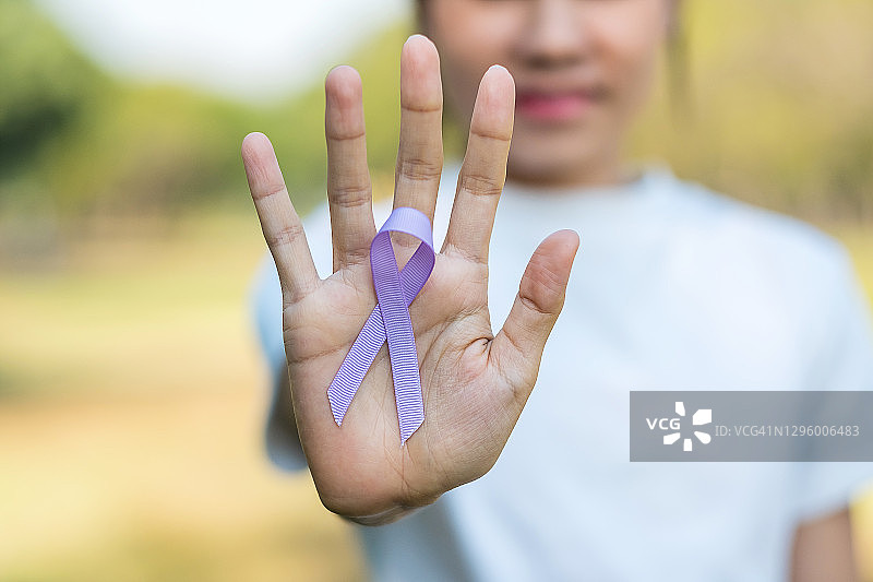 世界癌症日(2月4日)。妇女手持薰衣草紫色丝带支持人们生活和疾病。医疗保健理念图片素材