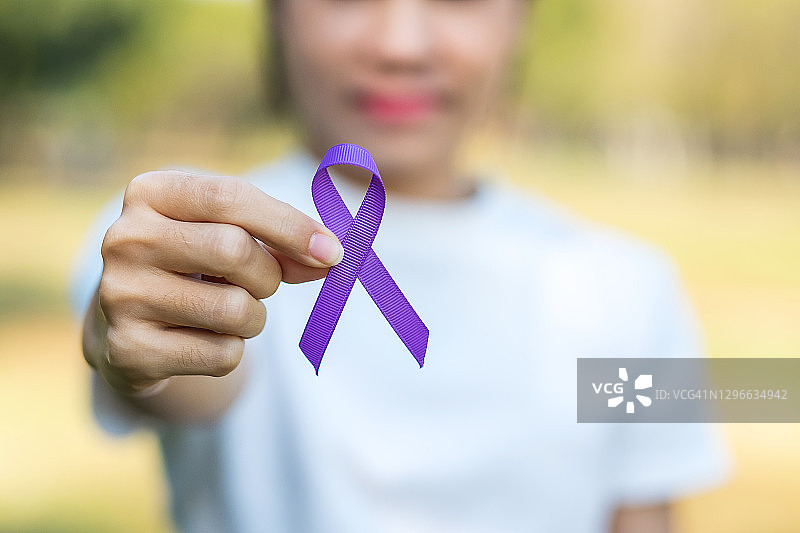 胰腺癌，世界阿尔茨海默病，癫痫，狼疮和家庭暴力日宣传月，妇女举着紫色丝带支持人们生活。医疗保健和世界癌症日概念图片素材