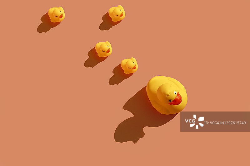 黄色的橡皮鸭在彩色的背景上排成一条线图片素材