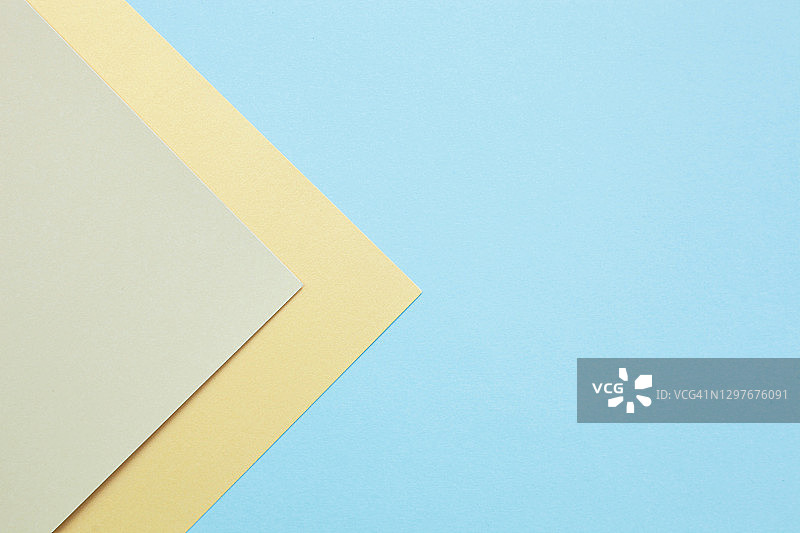 多色纸几何抽象背景的米色，黄色和蓝色柔和的颜色。图片素材