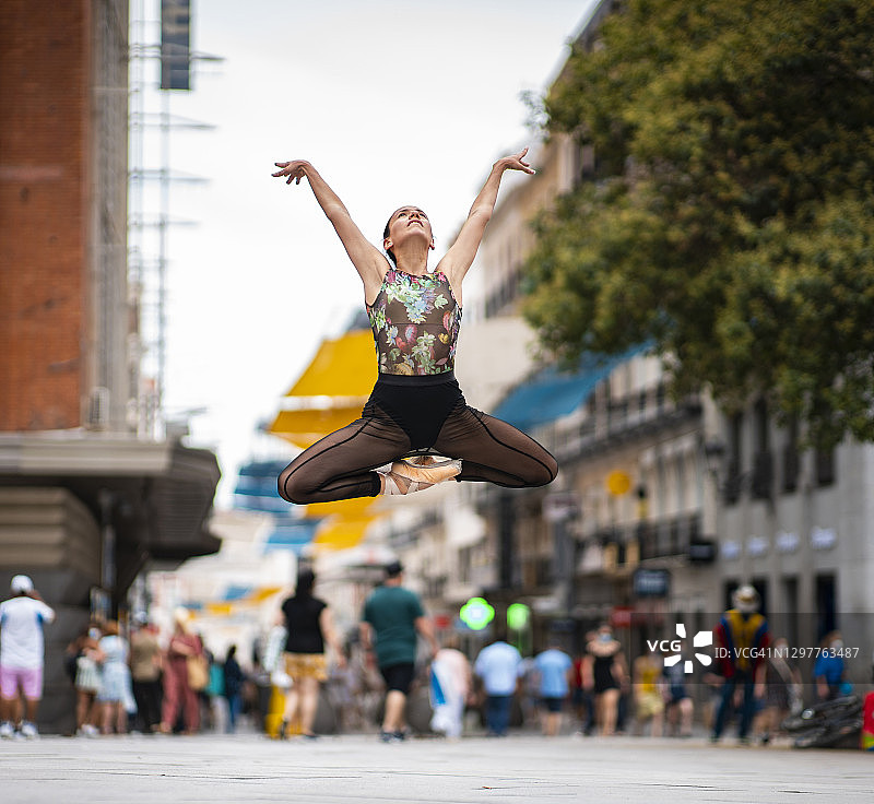 优雅的芭蕾舞者举起手在城市的街道上跳舞图片素材