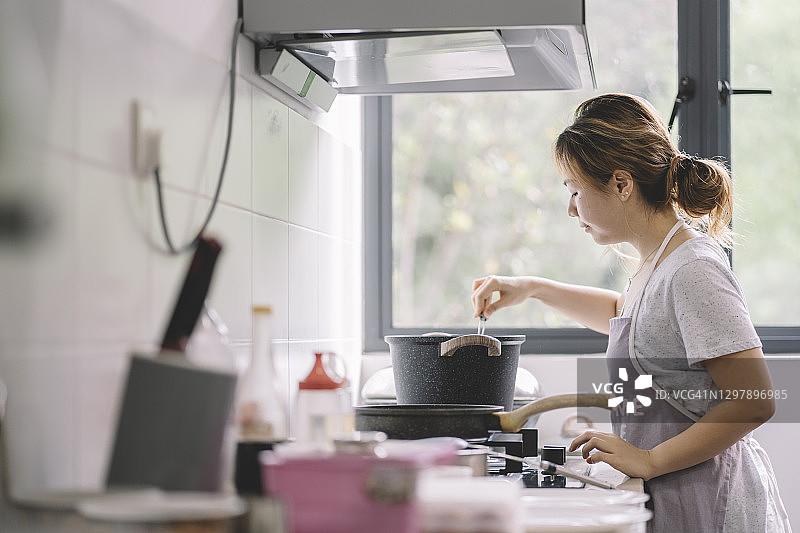 亚洲华人妇女在厨房做饭图片素材
