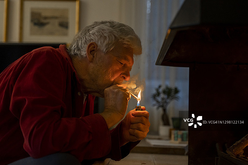 老人坐在家里用打火机点燃香烟图片素材
