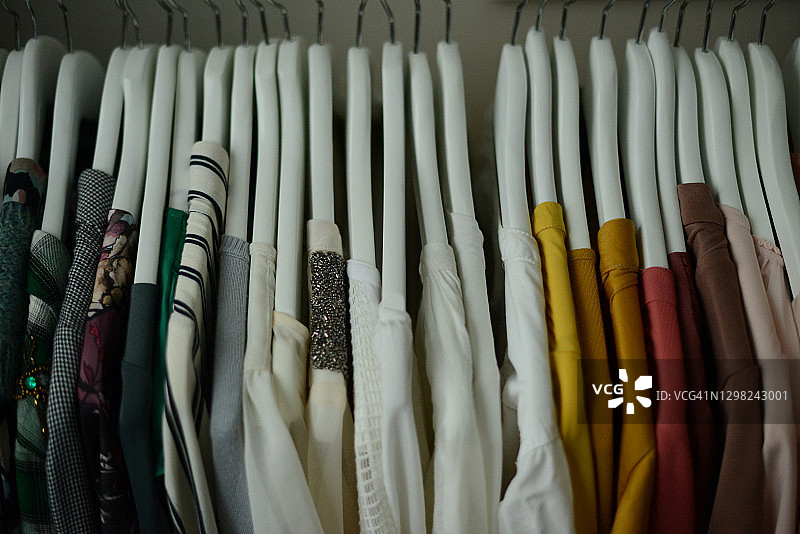 不同颜色的衬衫按颜色排列成一排挂在衣架上图片素材