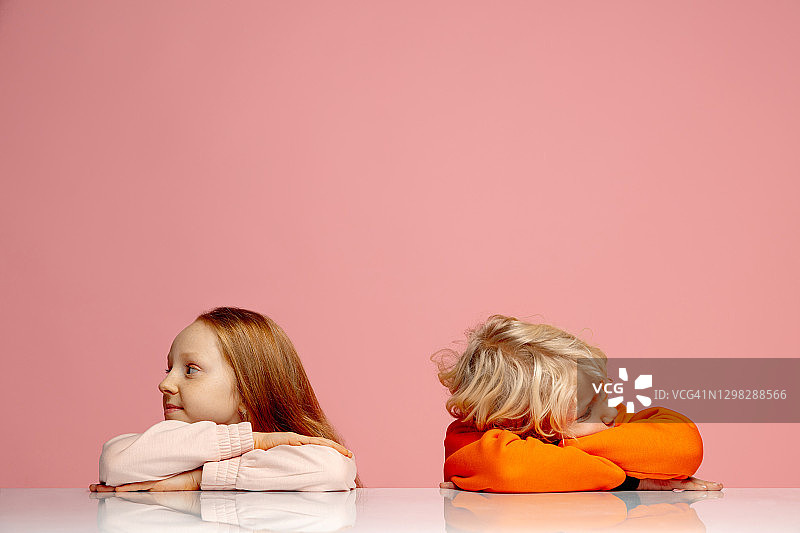 快乐的孩子隔离在珊瑚粉红色的工作室背景。看起来开心，开朗，真诚。Copyspace。童年，教育，情感概念图片素材