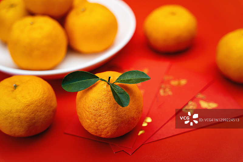 红色背景的橘子和红包。中国新年。图片素材