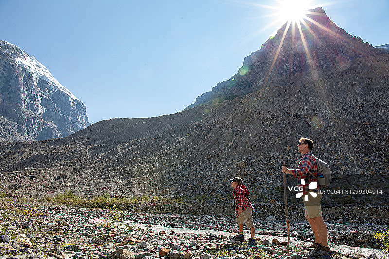 清晨，父子俩沿着阳光明媚的山谷徒步旅行图片素材