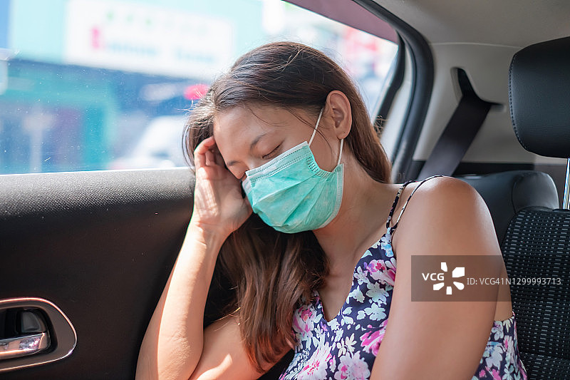 生病的中国妇女戴着口罩睡在汽车上图片素材
