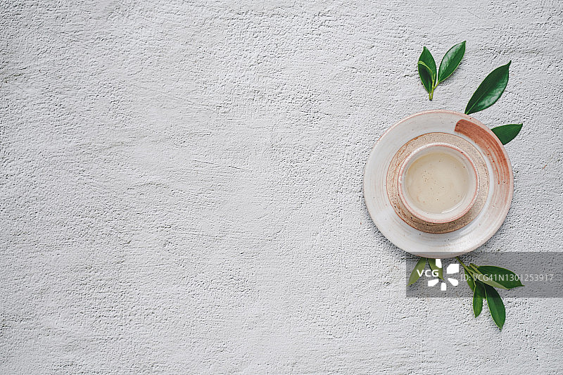 茶的概念，奶白茶具杯和茶壶周围的设备和新鲜茶叶在混凝土背景与复制空间。图片素材