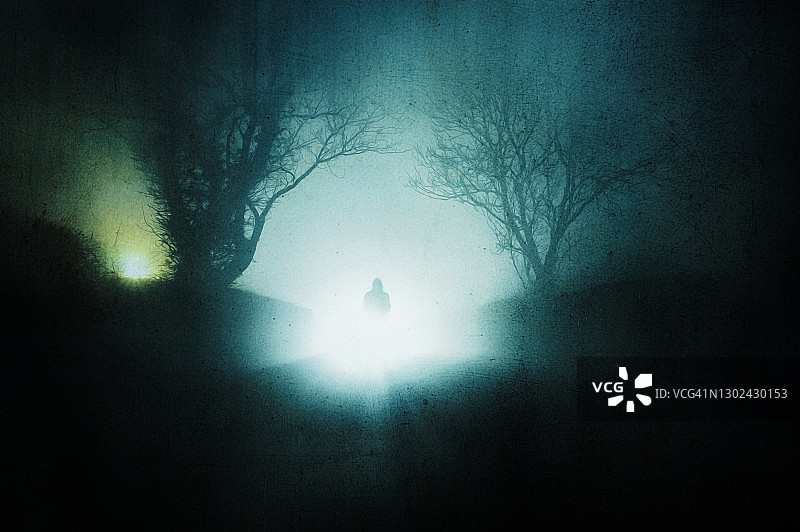 一个戴兜帽的幽灵。在一个雾蒙蒙的冬夜，我站在一条乡间小路上。用垃圾摇滚，艺术编辑图片素材