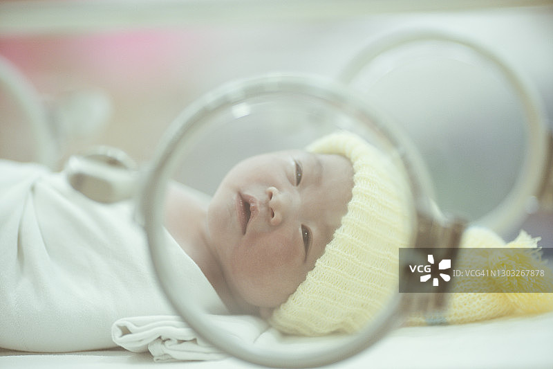 近距离观察亚洲新生婴儿在保温箱里昏昏欲睡的第一天图片素材