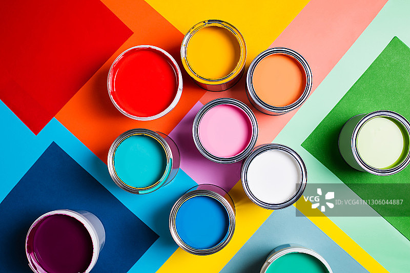 开罐上有鲜艳的彩色油漆，排列在彩色的几何背景上，分为几个部分，代表着家庭修理和装修用品的概念。表演在平lay风格。家居室内重新装修的概念。色卡f图片素材