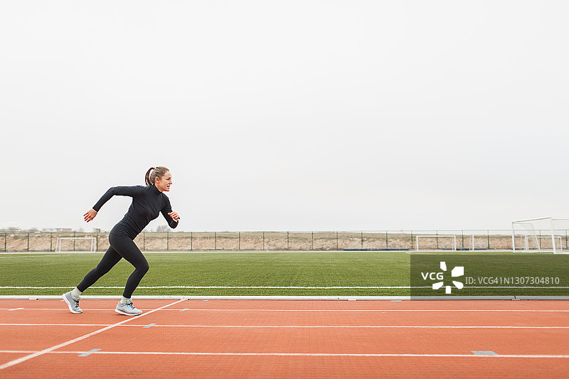 女运动员在体育场跑道上进行强力间歇跑训练和加速图片素材