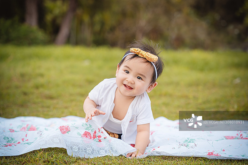 小女孩坐在毯子上玩得很开心。野餐。图片素材