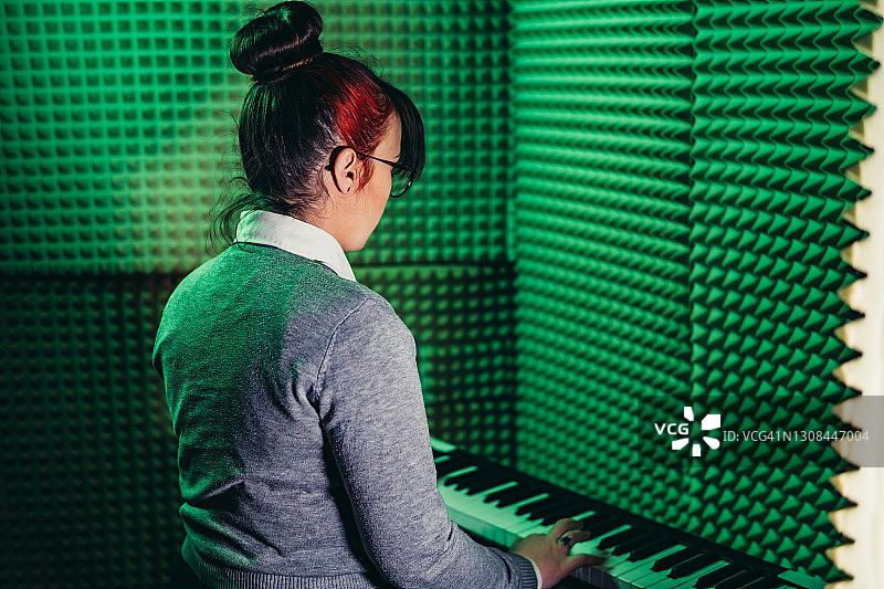 在录音室里弹奏数字钢琴的女人图片素材