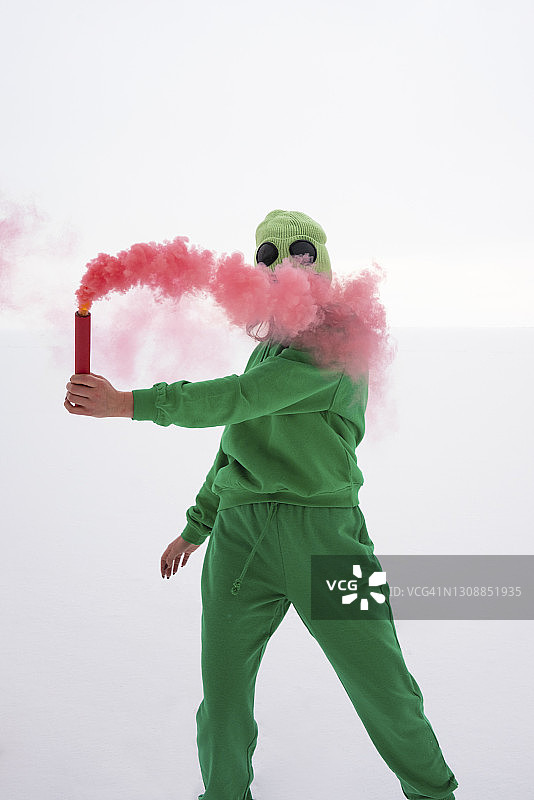 身着绿色服装的女子手持红色烟雾向天空求救图片素材