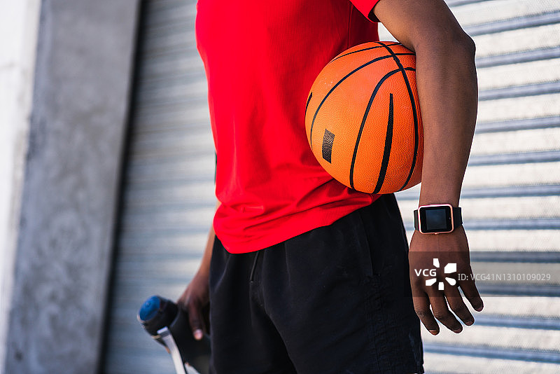 黑人运动员在户外拿着篮球。图片素材