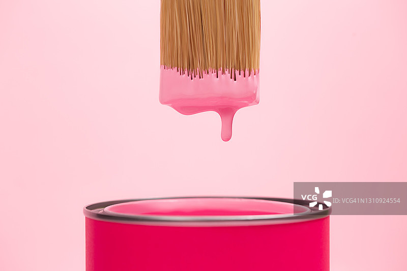 粉红色的颜料从画笔刷滴进粉彩背景的颜料罐中。家居维修的概念。前视图和特写图片素材